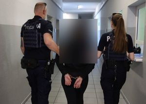 policjant i policjantka prowadzą zatrzymanego