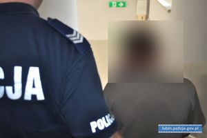 policjant prowadzi zatrzymanego