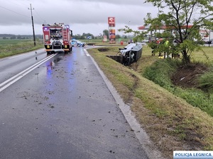 samochód w rowie obok straż pożarna i radiowóz