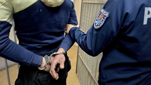 policjant prowadzi zatrzymanego mężczyznę skutego w kajdanki