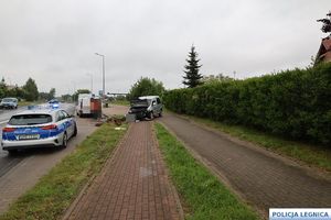 radiowóz na ulicy przed nim samochód ze zniszczonym przodem po zderzeniu z latarnią
