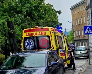 kobieta trzyma dziecko na rękach stojąc przed drzwiami karetki