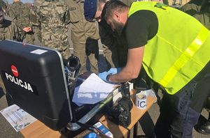 policjant w kamizelce odblaskowej przegląda dokumenty w walizce