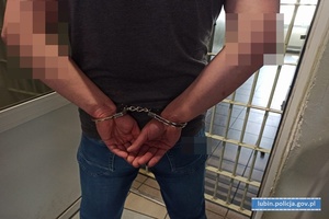 mężczyzna w kajdankach na rękach przed salą więzienną