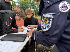 uczniowie klas mundurowych podpisują dokumenty
