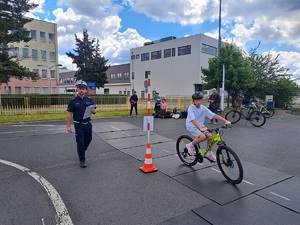 chłopak na rowerze pokonuje trasę turnieju, przygląda się temu policjant