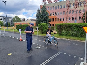 dziewczyna na rowerze pokonuje trasę turnieju, przygląda się temu policjant