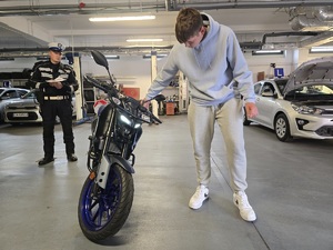 chłopak ogląda motor z tyłu stoi policjant