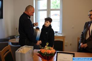 komendant wręcza prezent chłopcu