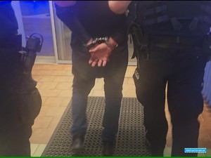 policjanci prowadzą zatrzymanego w kajdankach