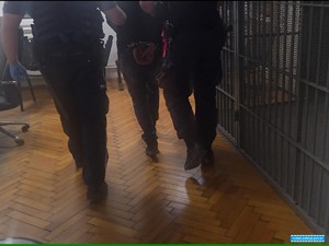 mężczyzna w kajdankach prowadzony jest do aresztu przez policjantów