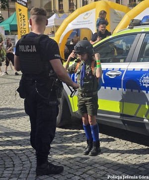policjant z harcerką zakładającą kask podczas festynu