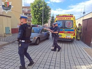 dwaj policjanci kolo ambulansu obok samochód osobowy i mężczyzna