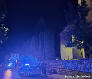 radiowóz i wóz strażacki wraz z policjantami i strażakami nocną porą przy kościele