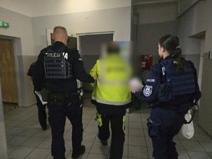 policjantka i policjant prowadzą mężczyznę kamizelce odblaskowej