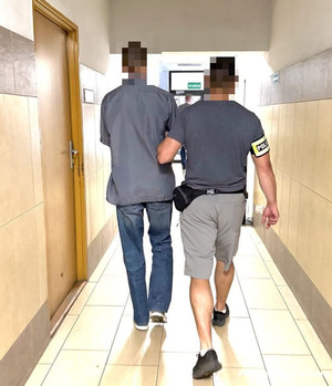 policjant w cywilnym ubraniu prowadzi zatrzymanego