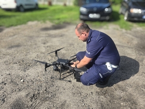 Umundurowani policjanci w trakcie wykonywania czynności służbowych, czyli kontrola drogowa oraz obsługa drona.