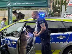 policjant przy radiowozie w którym siedzą dzieci podczas festynu