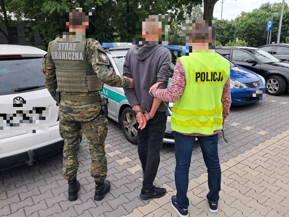 policjanci prowadzą zatrzymanego mężczyznę