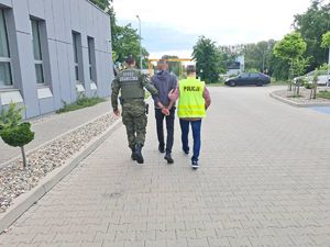 policjanci prowadzą zatrzymanego mężczyznę