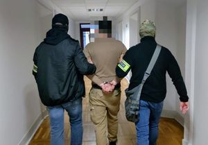 policjanci prowadzą zatrzymanego mężczyznę