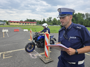 policjant jedzie motorem, obok policjant z gwizdkiem w ustach