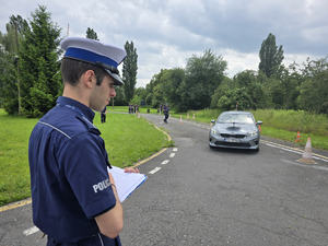 policjant oceniający konkurencję jazdy samochodem