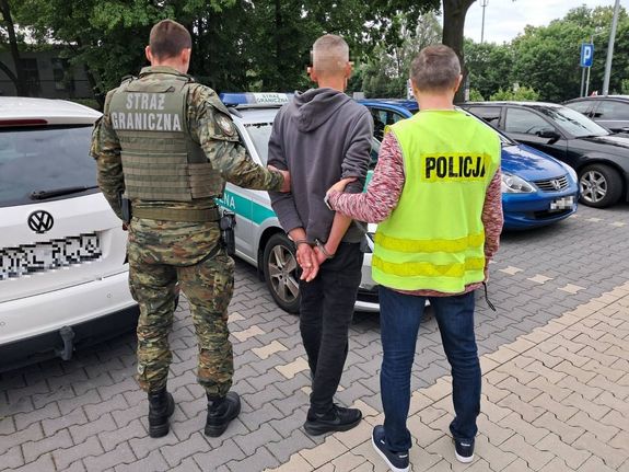 policjant i straż graniczna z zatrzymanym mężczyzną