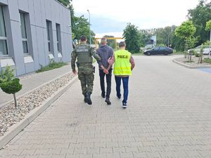 policjant i straż graniczna prowadzą zatrzymanego mężczyznę