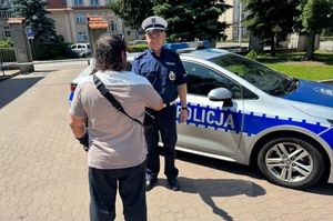 mężczyzna dziękuje policjantom stojącym przy radiowozie