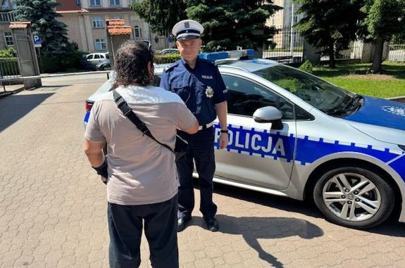 mężczyzna dziękuje policjantom stojącym przy radiowozie