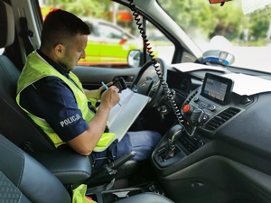 Policjant w radiowozie robi notatki