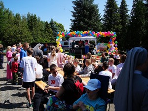 dzieci siedzące na ławkach podczas festynu na świeżym powietrzu