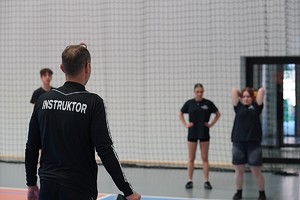 kobieta rzuca piłka lekarską przed nią stoi instruktor