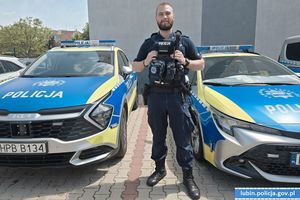 policjant stojący pośród dwóch radiowozów