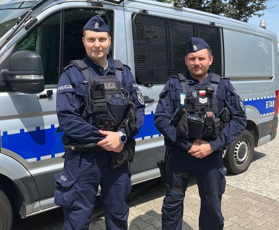 Umundurowani policjanci na tle radiowozu