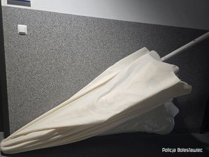 Parasol ogrodowy w kolorze białym oparty o ścianę