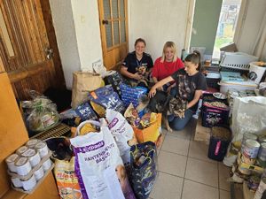 Policjantka i pracownice schroniska w korytarzu pełnym karmy i innych podarków dla ziwrząt