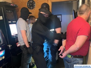 policjanci w kominiarkach wyprowadzają zatrzymanych mężczyzn z salonu do gier