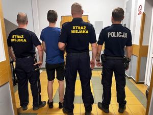 Policjant i strażnicy miejscy z zatrzymanym mężczyzną