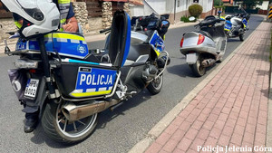 Oznakowany motocykl policyjny, zaparkowany wzdłuż chodnika.