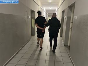 Policjant prowadzi zatrzymanego mężczyznę
