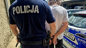 policjant prowadzi zatrzymanego skutego w kajdanki