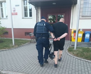 policjanci prowadzą zatrzymanego skutego w kajdanki