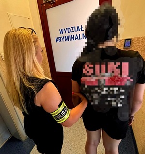 policjantka z zatrzymaną kobietą przed drzwiami wydziału kryminalnego