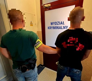 policjant z zatrzymanym przed drzwiami wydziału kryminalnego