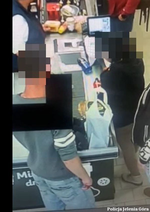 zdjęcie z kamery przemysłowej przedstawiające mężczyznę kradnącego plecak z kasy sklepowej
