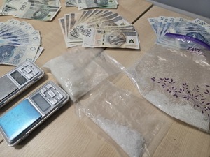 waga i rozłożone w wachlarz banknoty w nominale polskim i narkotyki w woreczkach
