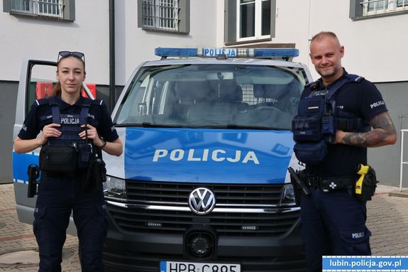 policjant i policjantka kolo radiowozu