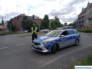 stojacy radiowóz z policjantem w kamizelce